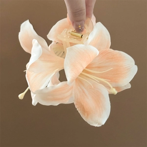 Close-up of artificial lily flower hair claw clip with delicate orange and white petals