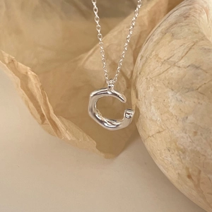 Macro shot of irregular 925 sterling silver C-shaped pendant with molten texture