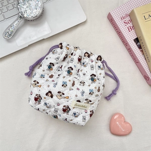 Flat lay of a quilted cartoon dog drawstring storage bag with lifestyle accessories