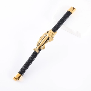 Macro detail of black braided leather bracelet featuring golden fishbone charm detail