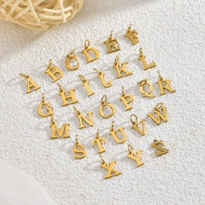 Flat lay of 26 gold alphabet pendants A-Z on woven background with natural lighting