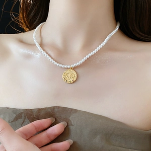 Vue détaillée du collier de perles avec pendentif œil porte-bonheur doré sur un mannequin