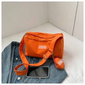 Détail d'un sac bandoulière orange en nylon avec sa pochette ronde et logo tendance