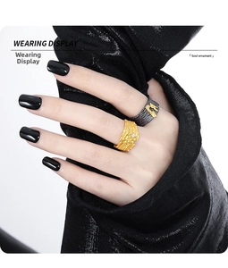 Detail view of irregular textured rings with crystals on model hand with black fabric