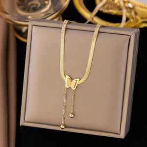 Gold butterfly necklace with beads tassel and flat snake chain on a brown jewelry box