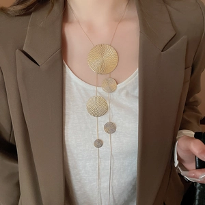 Detail of gold geometric circular fringe Y-necklace with textured metal plates on model