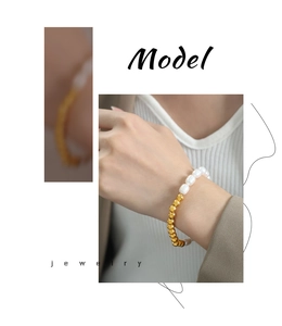 Detail of titanium steel bracelet featuring freshwater pearls and gold beads on wrist