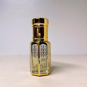 Macro shot of gold laser-coated glass perfume bottle with intricate filigree pattern