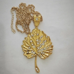 Macro view of gold maple leaf pendant with sparkling rhinestones and detailed leaf veins