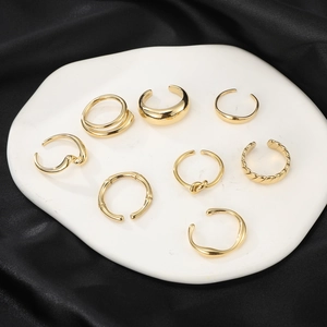 Set of 8 minimalist gold stainless steel rings with various textures on a white tray