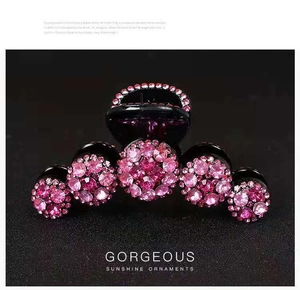 Dettaglio di un fermaglio per capelli nero con strass rosa brillanti su sfondo scuro