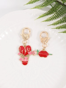 Detail of red heart balloon and lip charms with gold lobster clasp on white tray