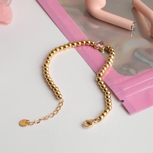 Luxurious gold beaded bracelet with a pink heart gemstone and adjustable lobster clasp