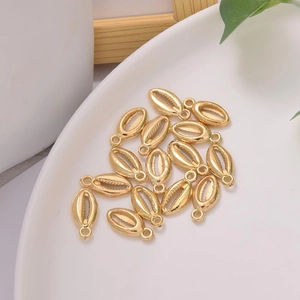 Golden cowrie shell charms on white plate for DIY jewelry making and necklaces