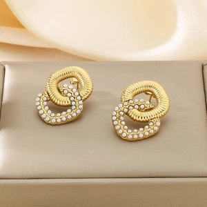 Macro detail of interwoven gold earrings with mini pearls and spiral textures