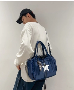 Detail of dark blue waterproof crossbody bag with star logo and checkered doll charm