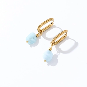 Detail view of gold U-shaped earrings featuring irregular light blue natural stones