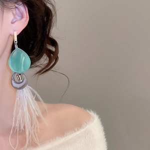 Détail des boucles d'oreilles bohèmes à pampilles en plumes et perles vertes sur modèle