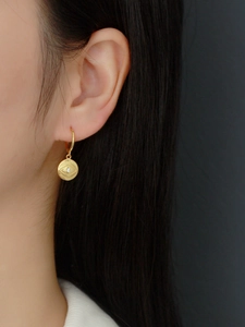 Close-up of gold S925 silver hoop earring with evil eye charm worn by model