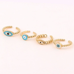 Macro view of four assorted gold Evil Eye rings with blue and white enamel details