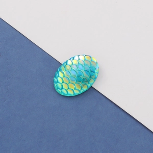 Macro shot of oval teal resin mermaid fish scale cabochon with iridescent AB finish