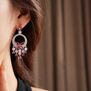 Detail of luxury butterfly drop earrings with pink zircons and tassels on model
