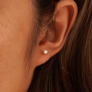 Close-up of a natural freshwater pearl stud earring worn on a woman's earlobe