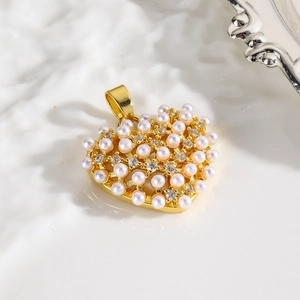 Detailed close-up of heart pendant with inlaid pearls and cubic zirconia on gold base