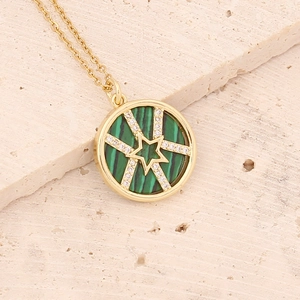 Gold necklace with green malachite pendant and star design on a stone surface