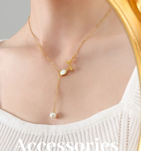 Detailed view of Y-shaped gold tulip necklace with pearl on model's neckline