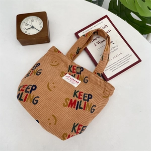 Detail of corduroy lunch bag with 'Keep Smiling' print and ZAKKA woven label text