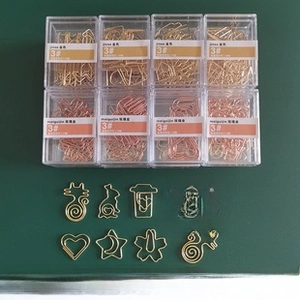 Close-up of creative gold and rose gold metal paper clips in cat and heart shapes