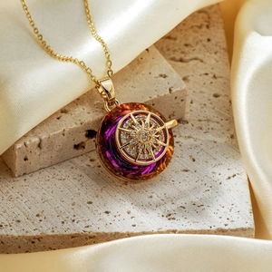 Macro detail of a gold sunburst pendant with purple gradient crystal on beige silk