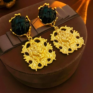 Detail of vintage lion head earrings with black stone studs on brown velvet box