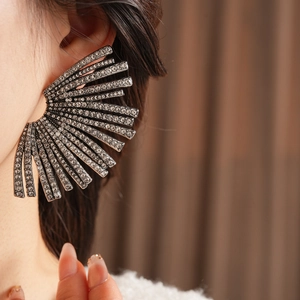 Macro view of crystal-encrusted fan-shaped earrings on model for a luxurious look