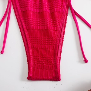 Vista macro dello slip bikini fucsia con trama goffrata e laccetti laterali regolabili