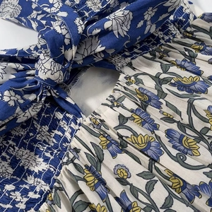 Detail of floral print dress featuring smocked fabric and an adjustable back tie bow