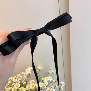 Detailed close-up of a black satin ribbon bow hair clip with elegant long streamers