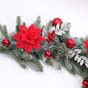 Dettaglio ghirlanda natalizia innevata con stelle di Natale rosse e pigne naturali
