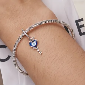 Mesh silver bracelet with evil eye key pendant and sparkling crystals on wrist