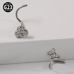 Macro shot of G23 titanium nose rings featuring detailed bee and butterfly designs