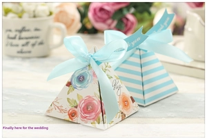 Detail of pyramid wedding favor boxes with floral patterns and silk blue ribbons