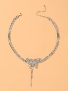 Detail of silver rhinestone butterfly choker with sparkling tassel on beige background