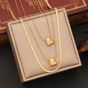 Detailed view of triple-layered gold necklaces with heart pendants and flat snake chain