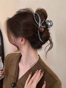 Detailed view of large black metal hair claw clip with amber bead in a hair bun style