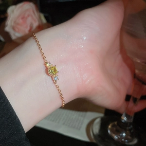 Detail of a gold-plated bracelet with yellow stone and zircons worn on a model's wrist
