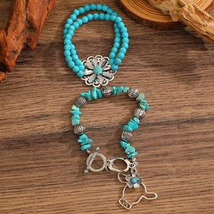Detail of vintage turquoise bull head bracelet and ring set on rustic wood surface