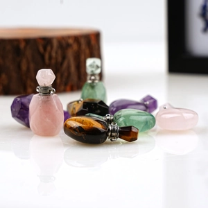 Macro shot of assorted natural crystal perfume bottle pendants on a reflective surface