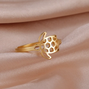 Detailed view of hollow turtle ring in 18K gold plated stainless steel on pink silk
