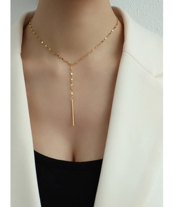 Collier en Y de style français avec pendentif barre dorée porté par un mannequin femme